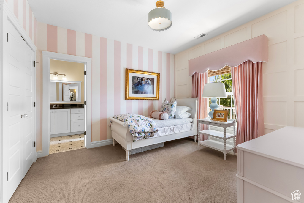 Bedroom featuring light carpet, wallpapered walls, and ensuite bath