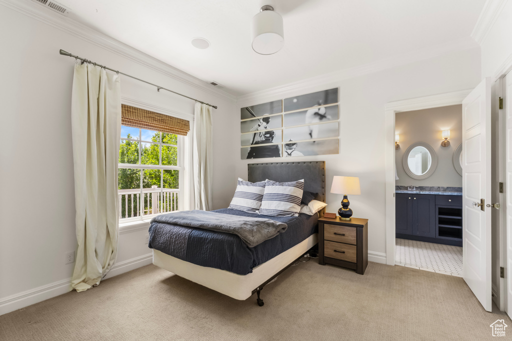 Bedroom featuring ornamental molding, light carpet, and ensuite bath