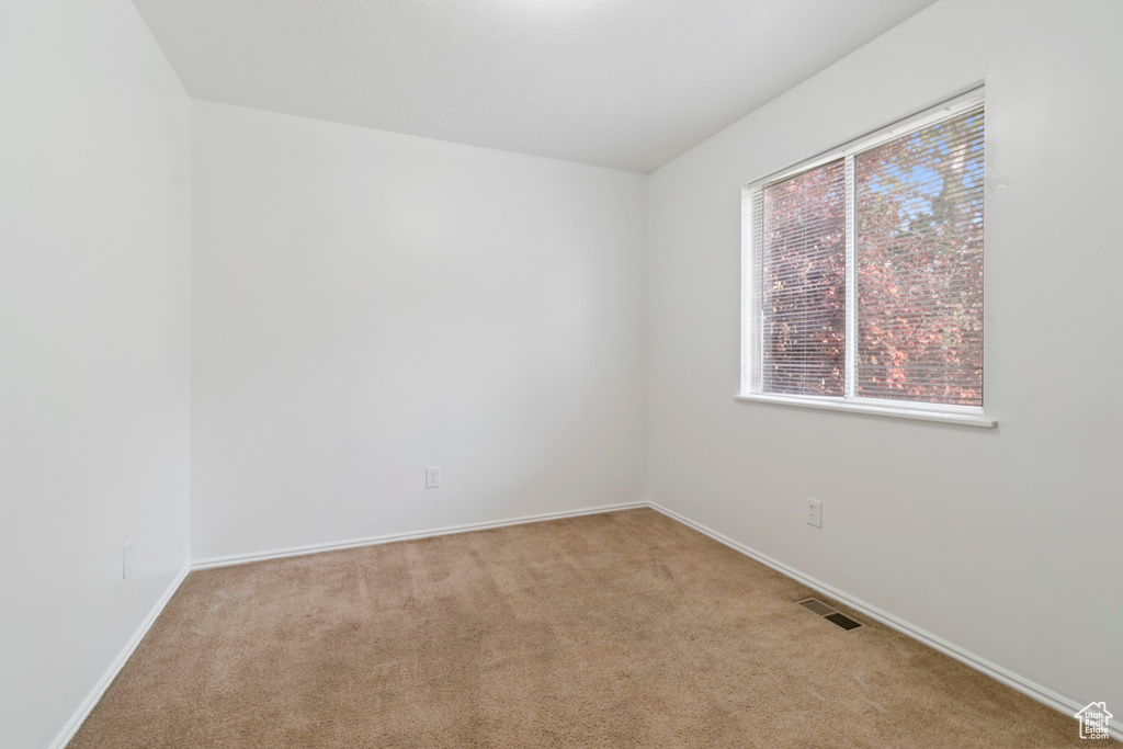 Empty room with light colored carpet and baseboards