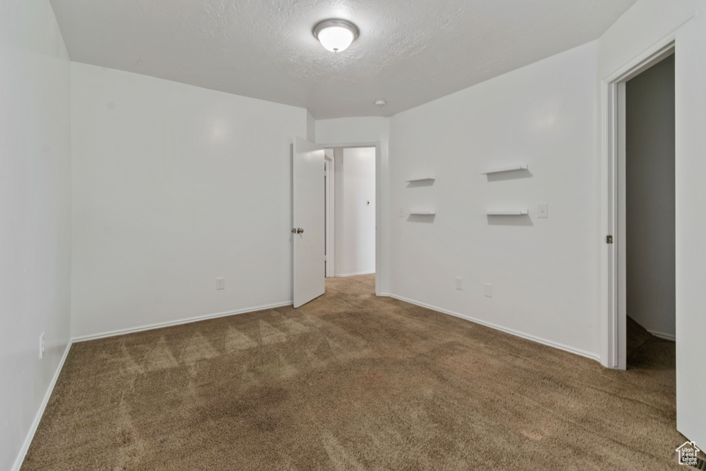 Empty room with carpet and a textured ceiling