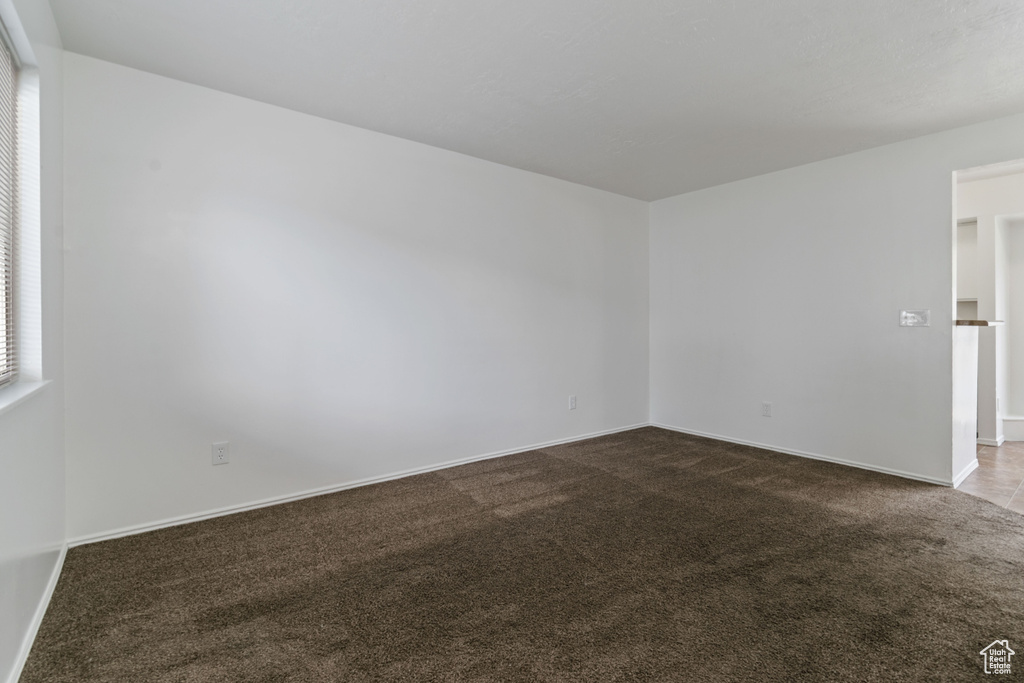 Spare room featuring dark carpet and baseboards
