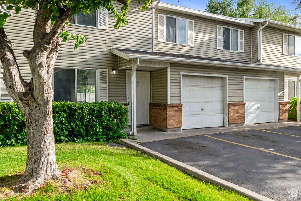 Multi unit property featuring an attached garage, brick siding, and asphalt driveway