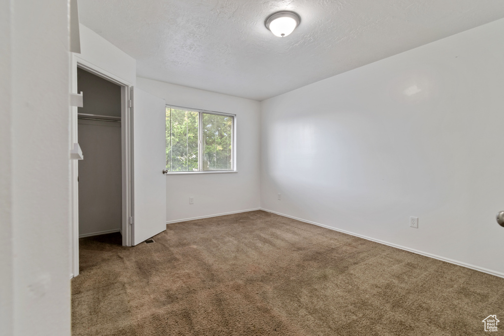 Unfurnished bedroom featuring carpet, a textured ceiling, and a closet