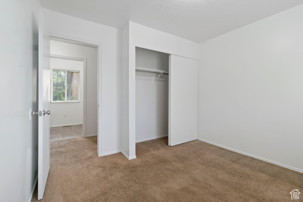 Unfurnished bedroom featuring carpet and a closet