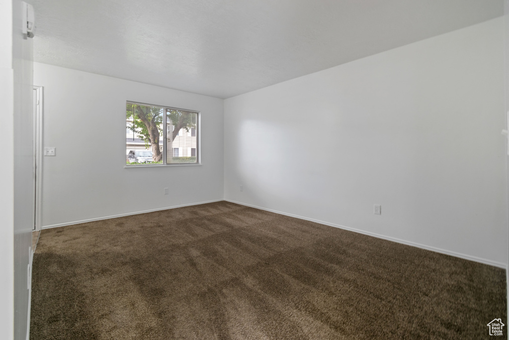 Unfurnished room featuring dark carpet and baseboards