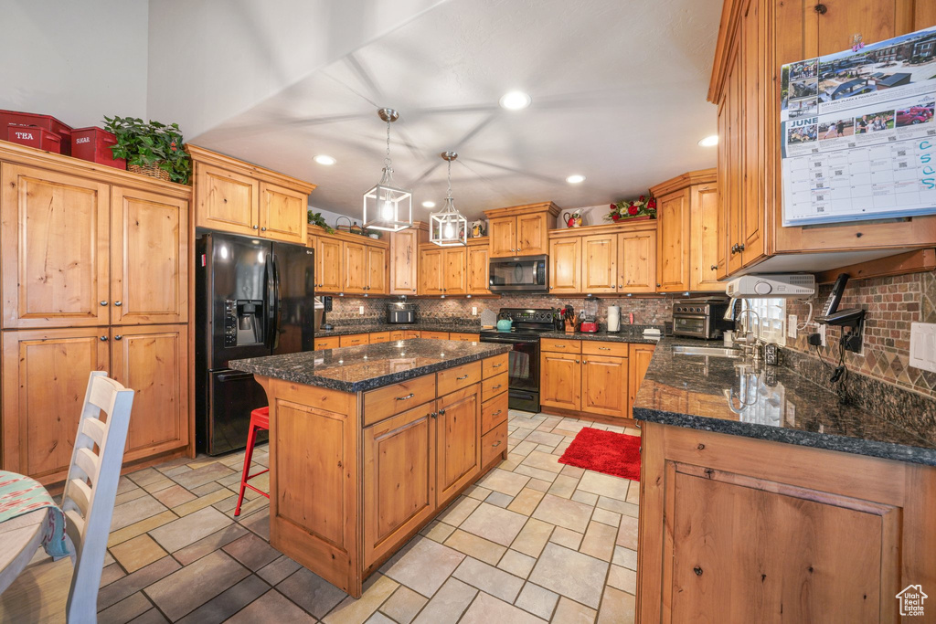 Kitchen featuring black appliances, decorative backsplash, a center island, recessed lighting, and decorative light fixtures