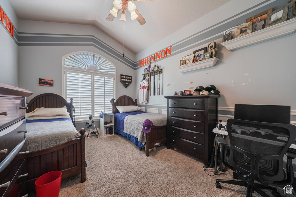 Carpeted bedroom featuring vaulted ceiling, an office area, and ceiling fan