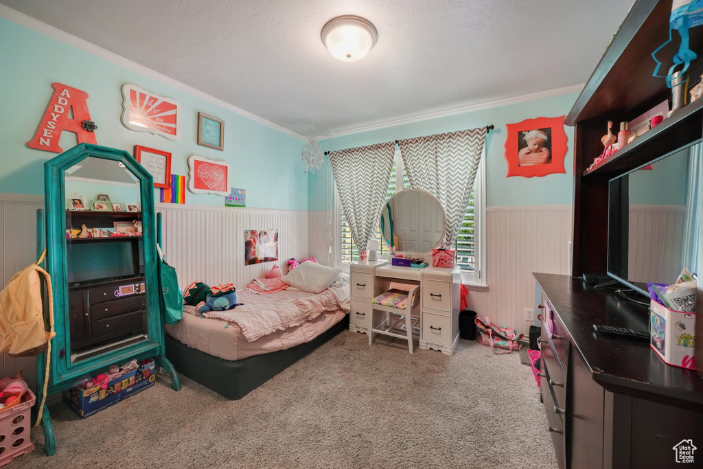 Bedroom featuring a wainscoted wall, crown molding, and carpet flooring