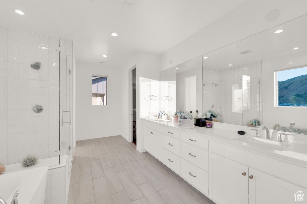 Bathroom with a shower stall, double vanity, recessed lighting, and a garden tub