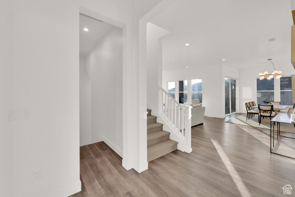 Foyer entrance with wood finished floors, stairway, a chandelier, and recessed lighting