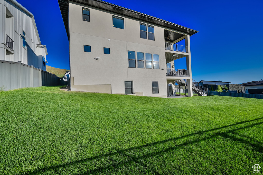 Rear view of house featuring a balcony, stairway, a ceiling fan, and stucco siding