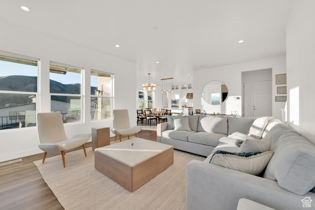 Living area with light wood finished floors, a chandelier, a mountain view, and recessed lighting
