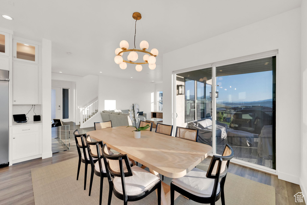 Dining room with stairway, wood finished floors, a chandelier, and recessed lighting