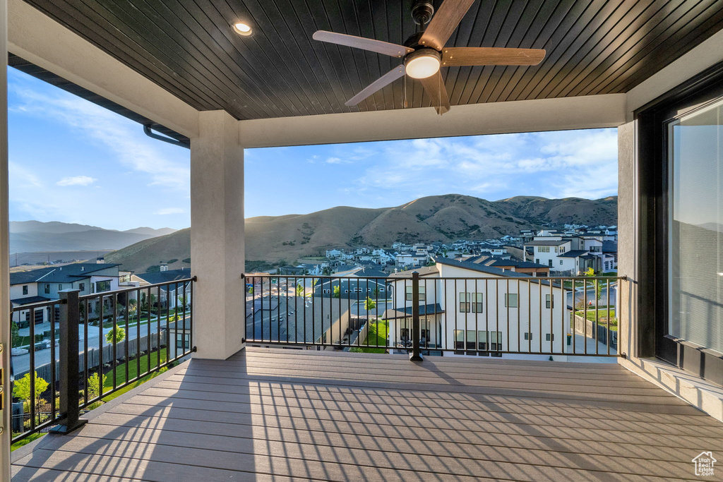 Wooden deck featuring a mountain view, a ceiling fan, and a residential view