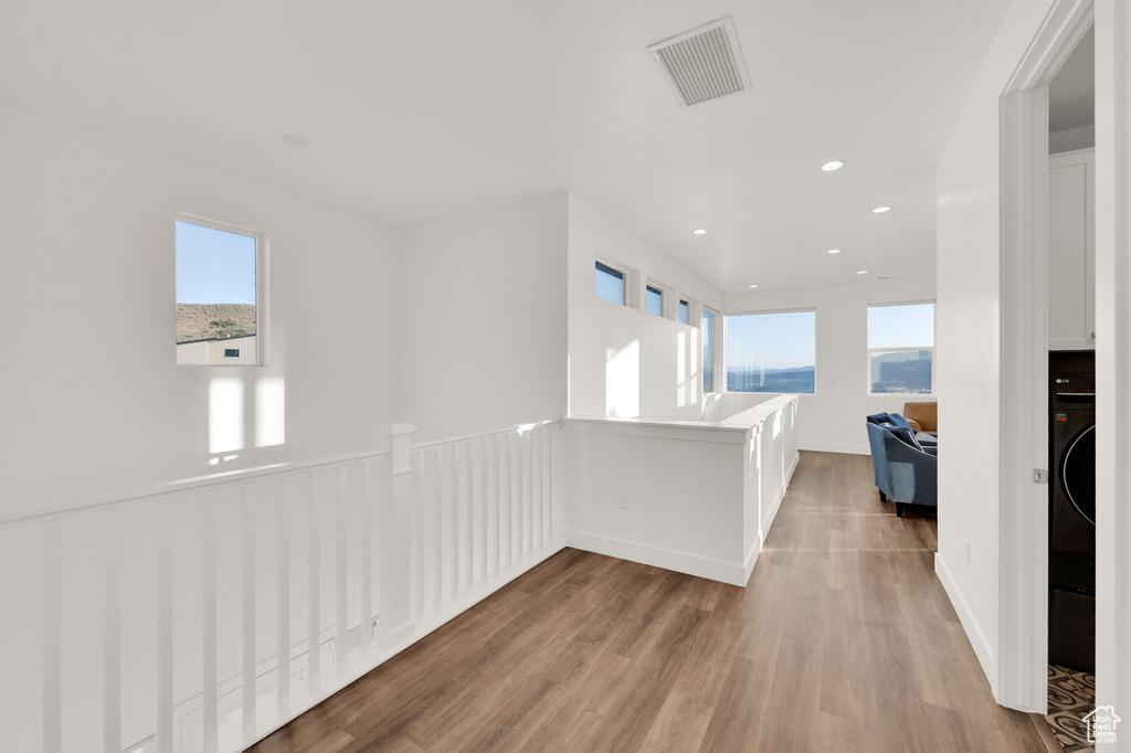 Hallway featuring plenty of natural light, light wood-style flooring, and recessed lighting