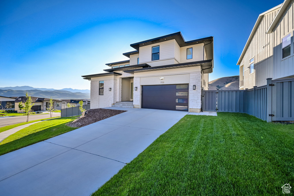 View of front facade with concrete driveway, a garage, a mountain view, and a gate