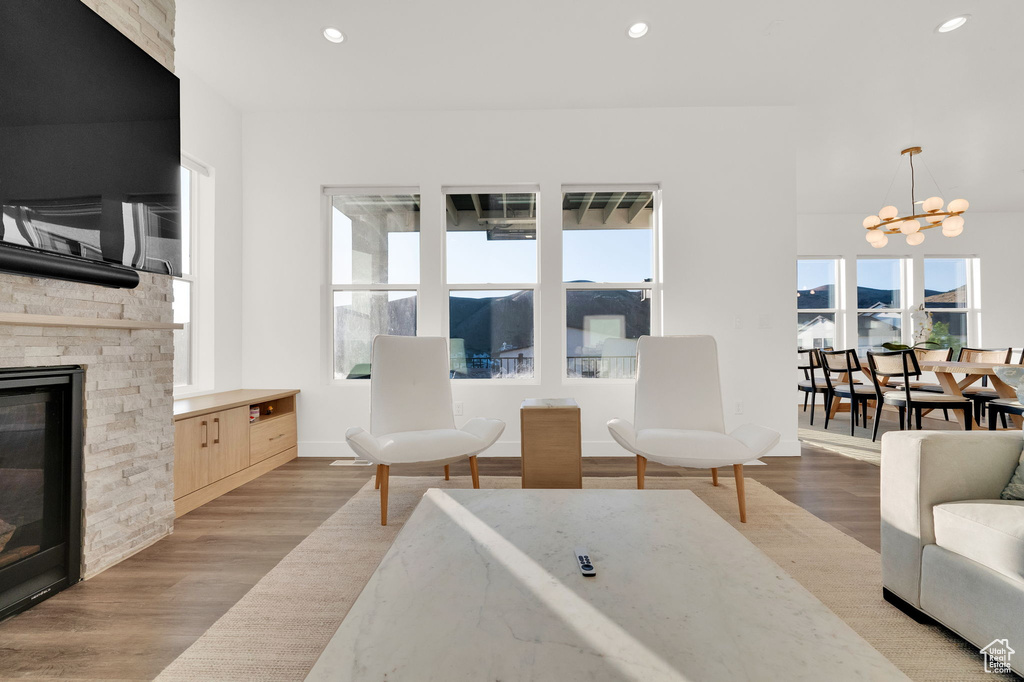 Living room featuring a chandelier, light wood-style floors, recessed lighting, and a stone fireplace