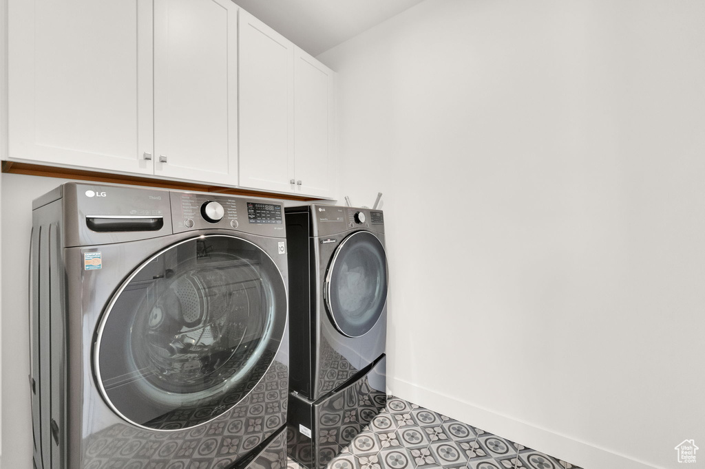 Washroom with independent washer and dryer, cabinet space, and tile patterned flooring
