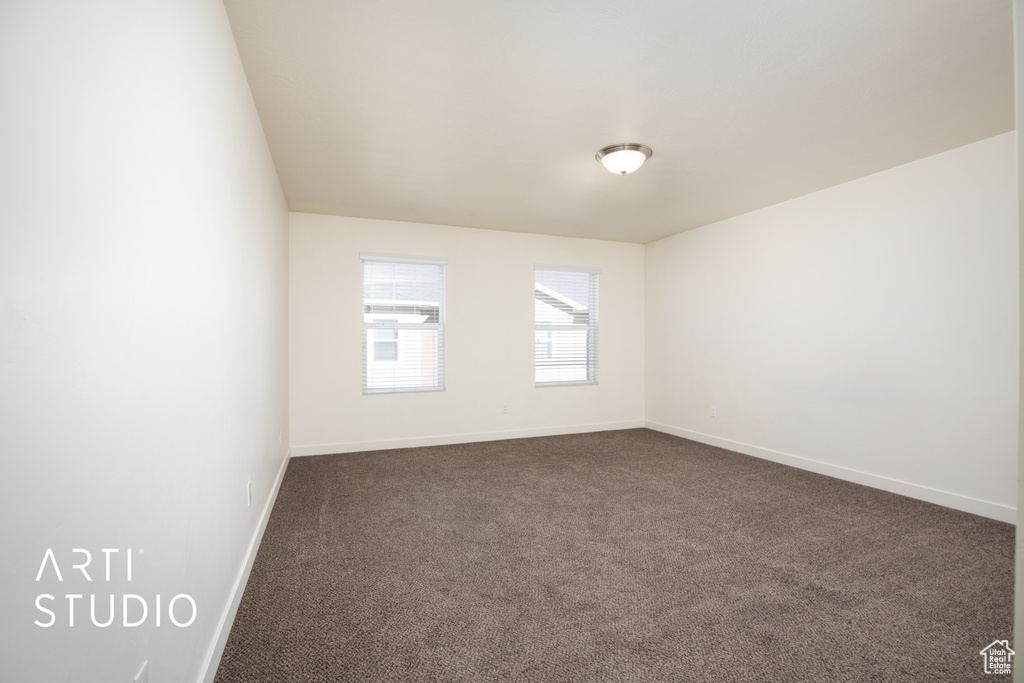 Spare room with dark carpet and baseboards