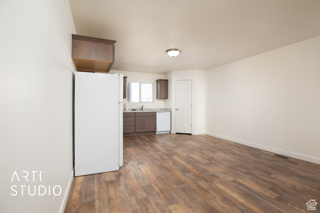 Kitchen with white appliances, dark wood-type flooring, and light countertops