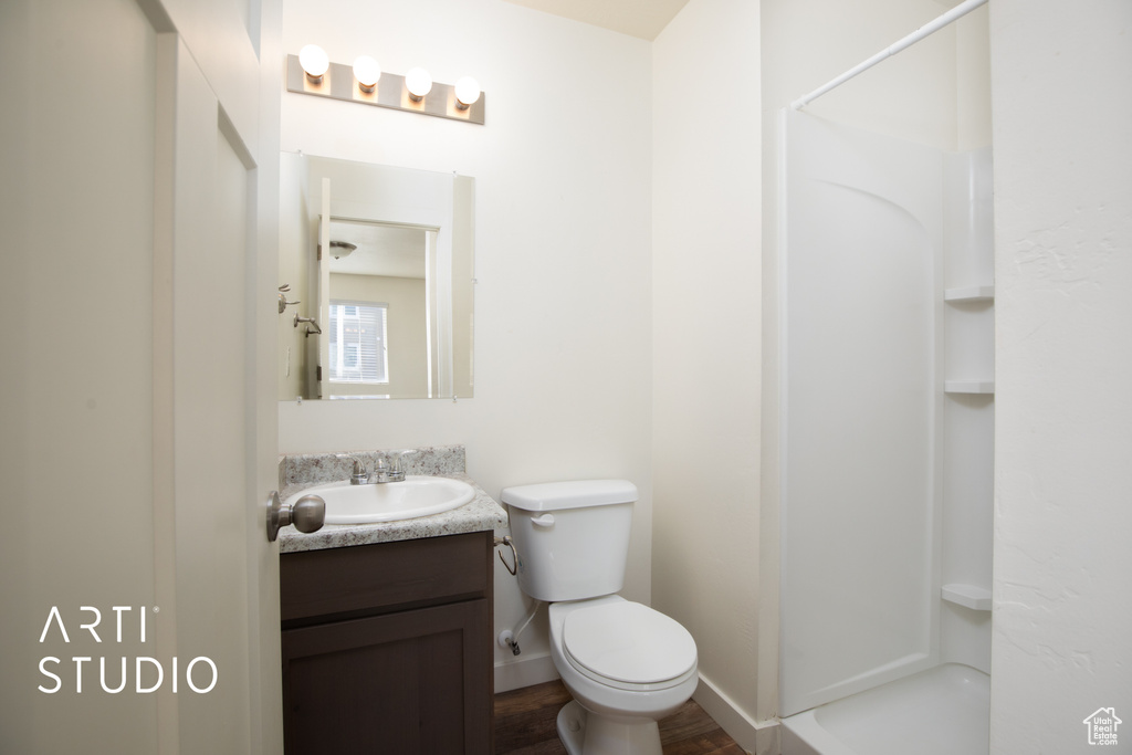 Bathroom featuring a shower, vanity, and wood finished floors