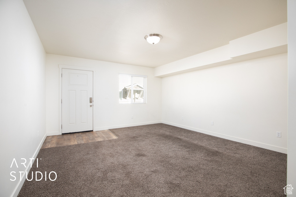 Spare room featuring dark carpet and baseboards