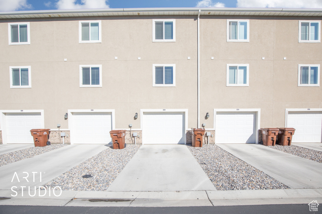 View of property with a garage and concrete driveway
