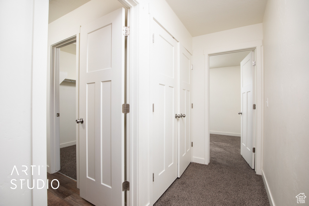 Hallway with dark carpet and baseboards