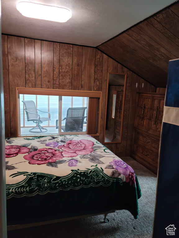 Carpeted bedroom with wooden walls and vaulted ceiling