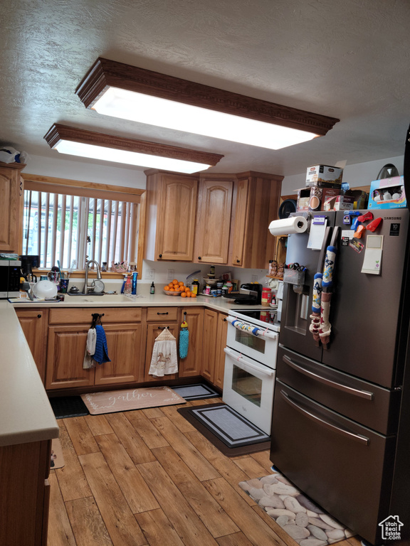 Kitchen featuring stainless steel appliances, light countertops, light wood-style floors, and a textured ceiling