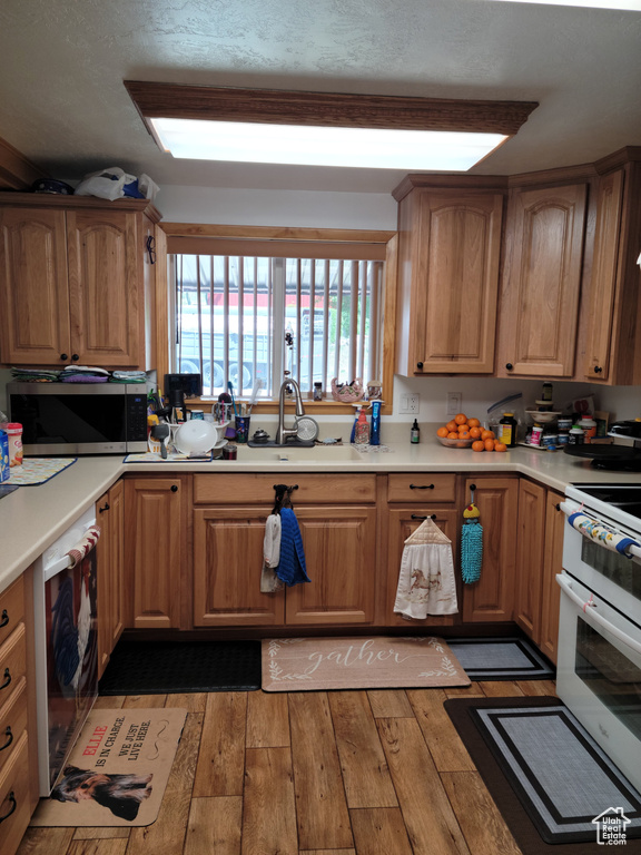 Kitchen with stainless steel microwave, range with two ovens, light wood-style floors, and light countertops