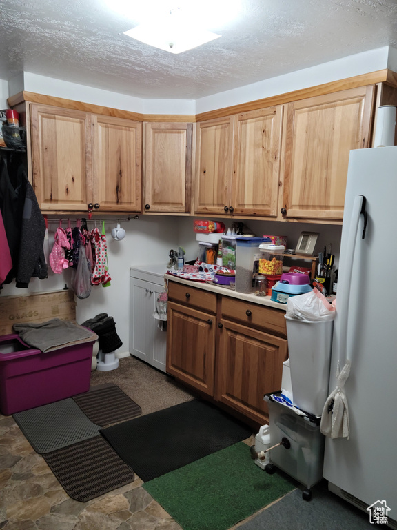 Kitchen featuring freestanding refrigerator, a textured ceiling, and light countertops