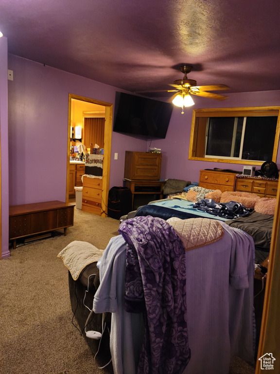 Bedroom with light carpet, connected bathroom, and ceiling fan