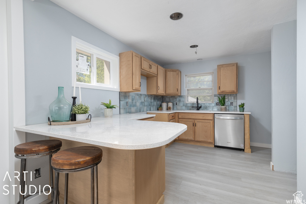 Kitchen featuring stainless steel dishwasher, a sink, a peninsula, and healthy amount of natural light