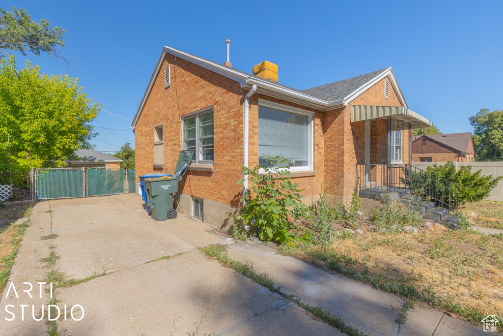View of front of home with brick siding, a chimney, and a gate