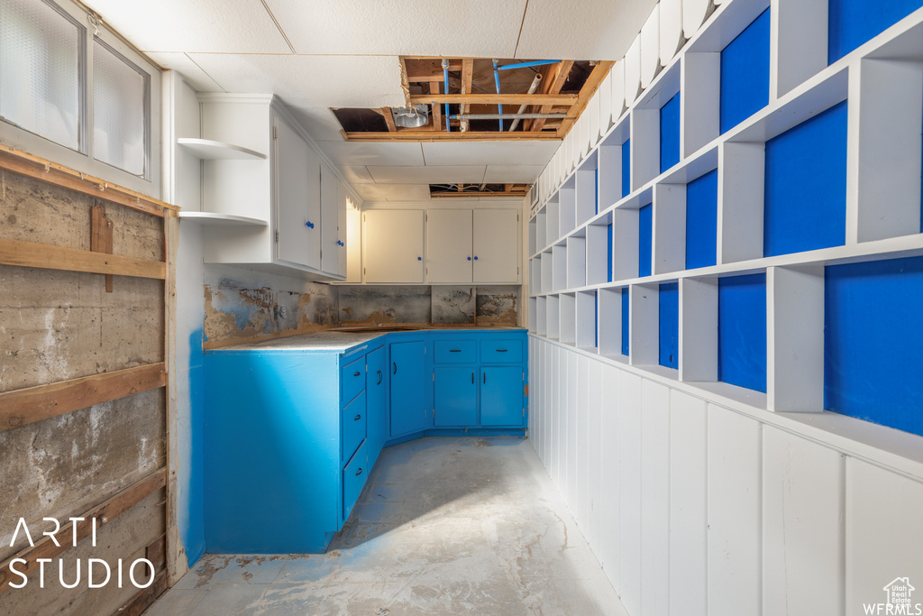 Kitchen with open shelves, unfinished concrete flooring, and blue cabinets