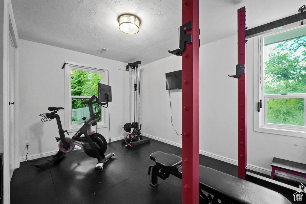 Workout room with a textured ceiling and baseboards