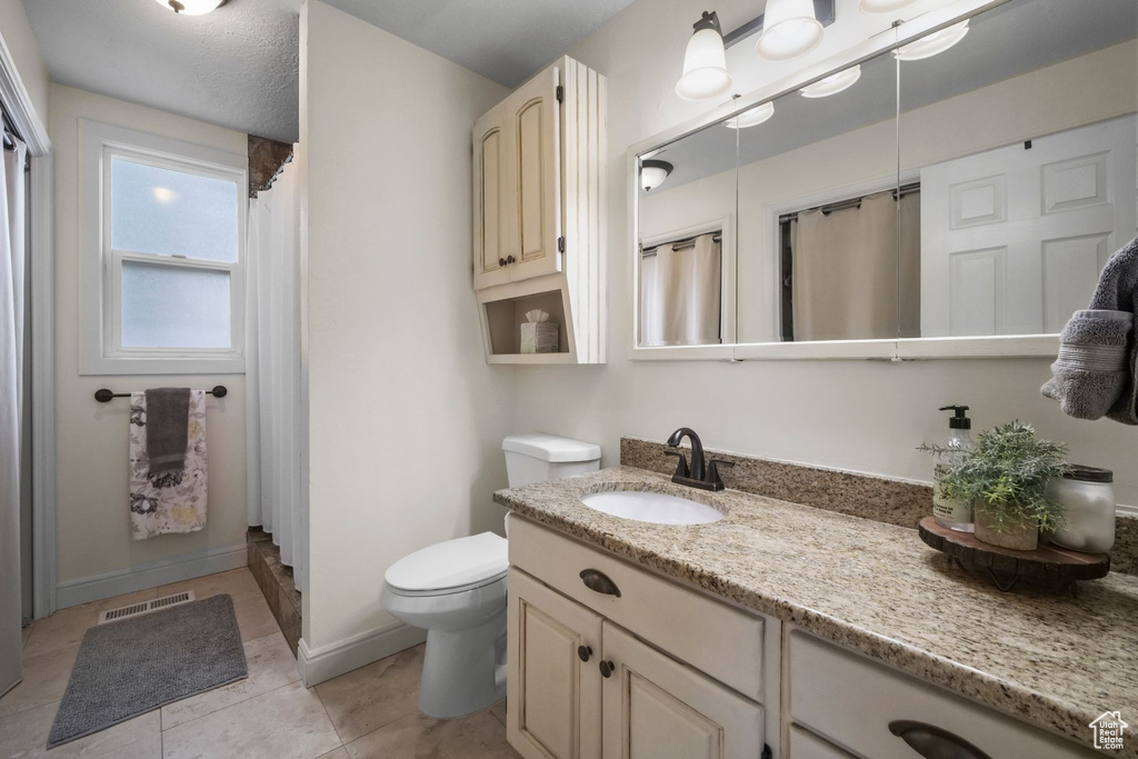 Full bath with vanity, curtained shower, and tile patterned flooring