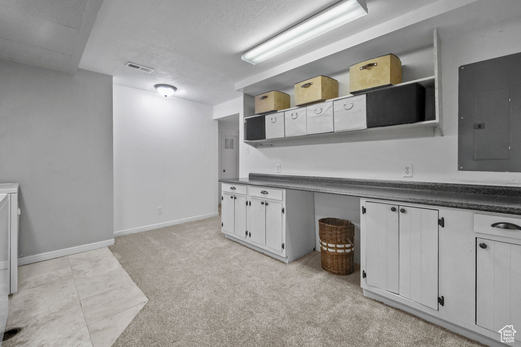 Kitchen with open shelves, electric panel, dark countertops, a textured ceiling, and white cabinets