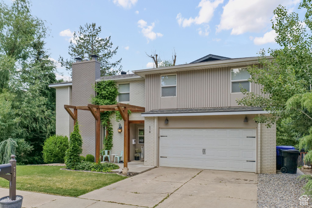 Townhome / multi-family property featuring brick siding, driveway, and an attached garage