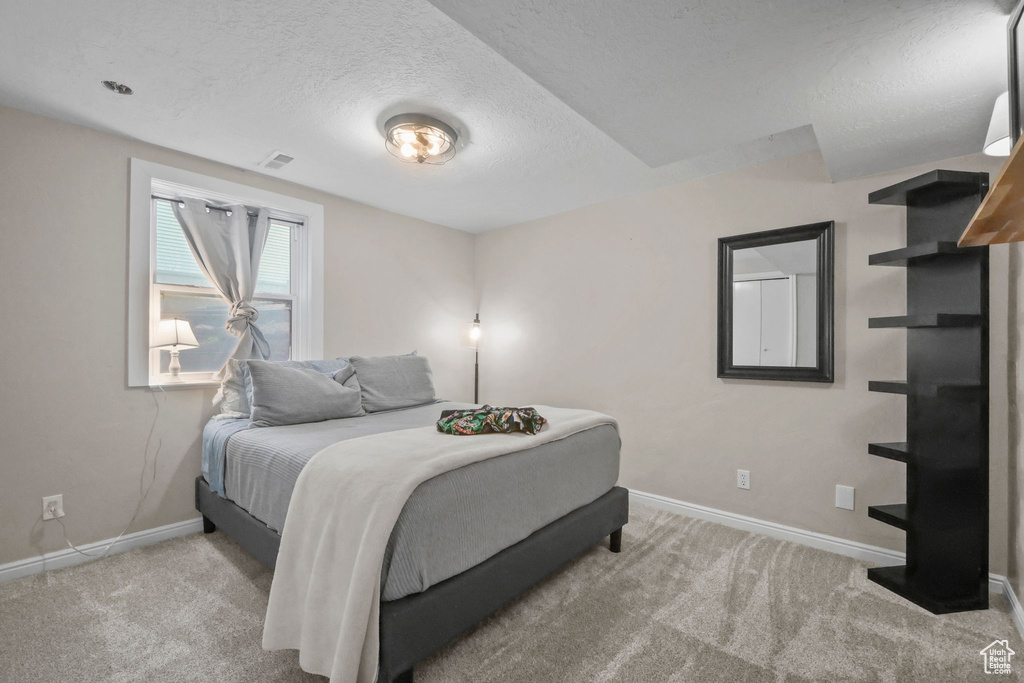 Bedroom with a textured ceiling and carpet