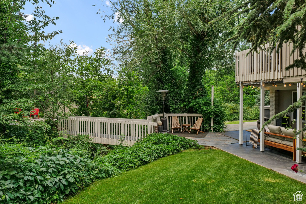 View of green lawn featuring a wooden deck and outdoor lounge area