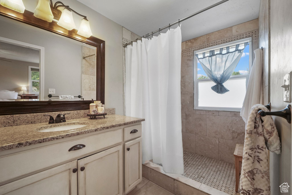Ensuite bathroom with healthy amount of natural light, a tile shower, and vanity