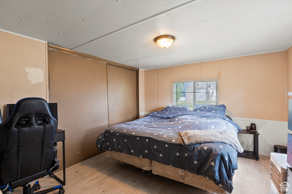 Bedroom featuring wood finished floors, a closet, a wainscoted wall, and a decorative wall