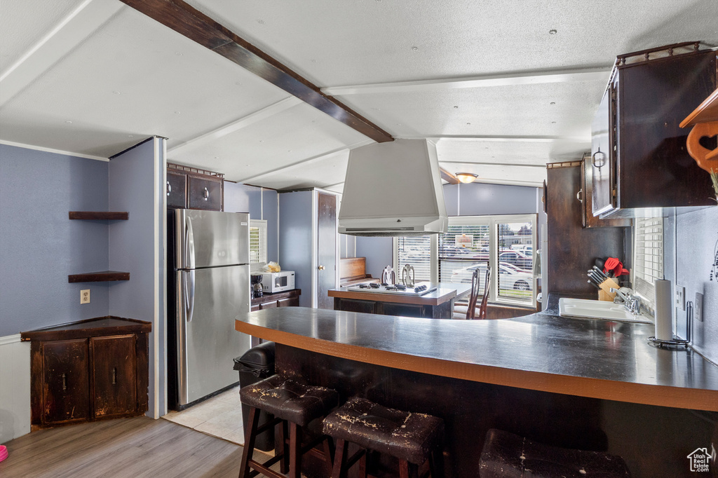 Kitchen with white appliances, custom exhaust hood, light wood-style floors, a peninsula, and dark brown cabinetry