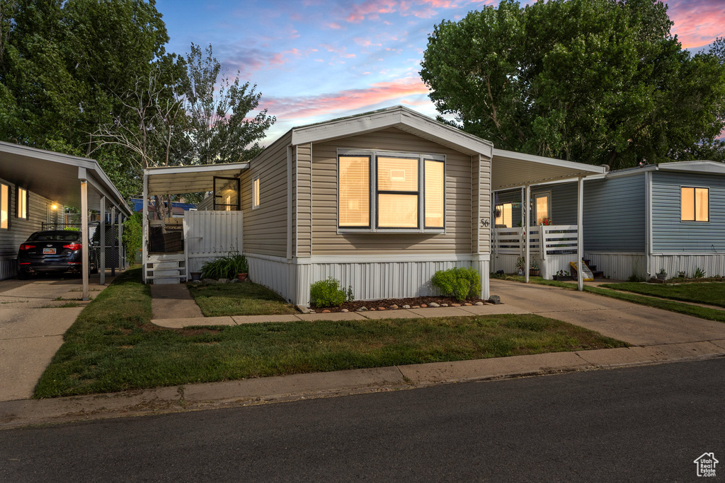 Manufactured / mobile home with driveway, a carport, a porch, and a yard