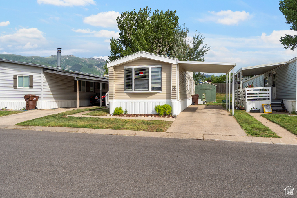 Manufactured / mobile home with an attached carport, a shed, concrete driveway, and a mountain view