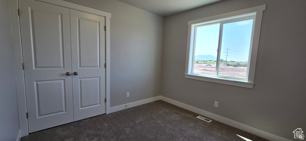 Unfurnished bedroom with dark colored carpet and a closet