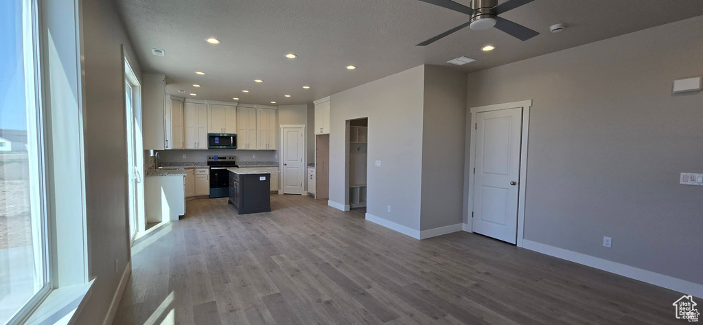 Kitchen with electric range, recessed lighting, open floor plan, ceiling fan, and light wood-style floors