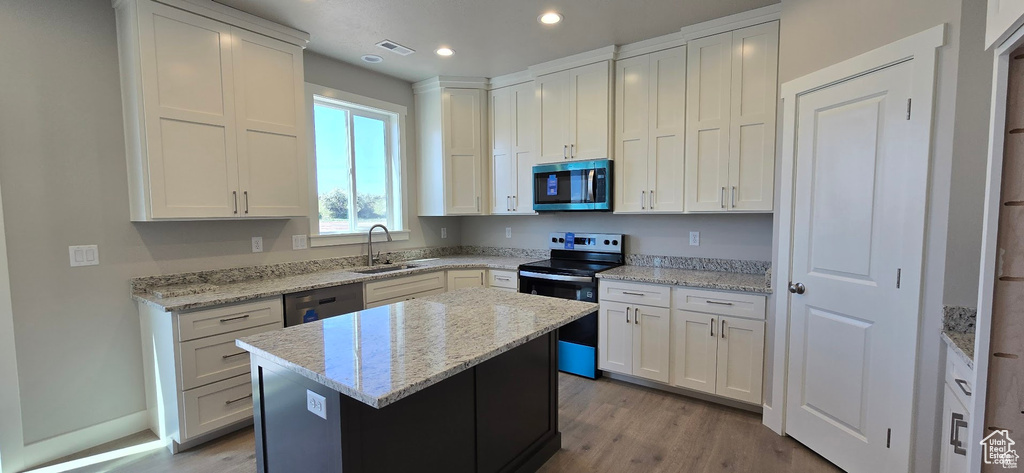 Kitchen with stainless steel appliances, a kitchen island, white cabinetry, and recessed lighting